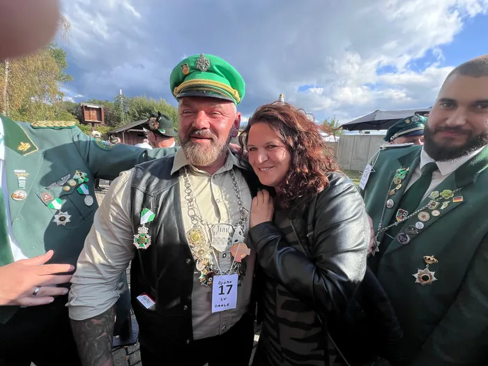 Ein Mann mit grüner Kappe und reich geschmückter Weste posiert lächelnd mit einer Frau beim Kreiskönigsschießen 2026.