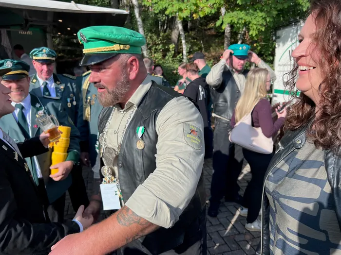 Männer in Schützenuniformen mit grünen Mützen beim Kreiskönigsschießen 2026; ein Mann schüttelt jemandem die Hand.