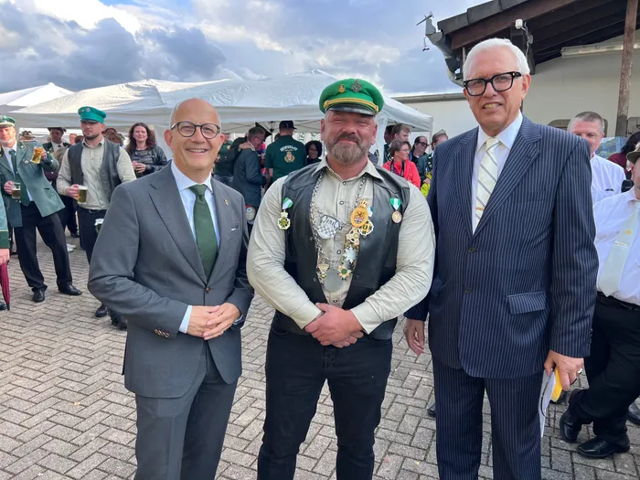 Drei Männer posieren beim Kreiskönigsschießen 2026, einer davon trägt eine mit Orden geschmückte Weste und eine grüne Kappe.