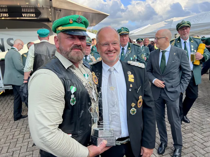 Zwei Männer mit Orden und einer grünen Schützenmütze halten eine kleine Trophäe beim Kreiskönigsschießen 2026.