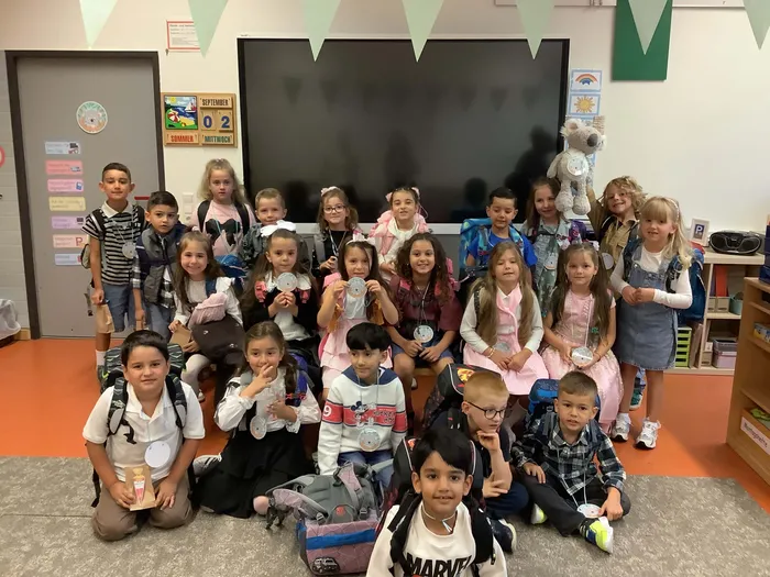 Die Kinder der Koala-Klasse 1a der Martin-Luther-Schule posieren für ein Gruppenfoto in ihrem Klassenzimmer.