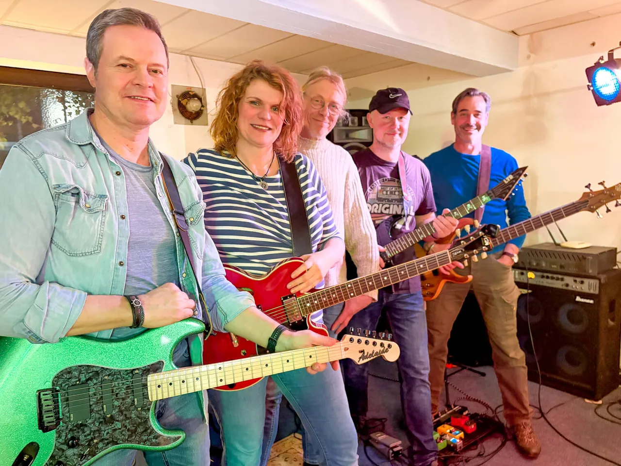 Fünf Musiker mit Gitarren stehen lächelnd in einem Raum mit Musikinstrumenten und Verstärkern. Die Band Maryland gibt ihr Debüt beim Raukfest.