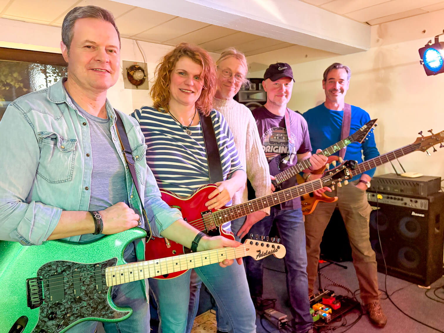 Fünf Musiker mit Gitarren stehen lächelnd in einem Raum mit Musikinstrumenten und Verstärkern. Die Band Maryland gibt ihr Debüt beim Raukfest.