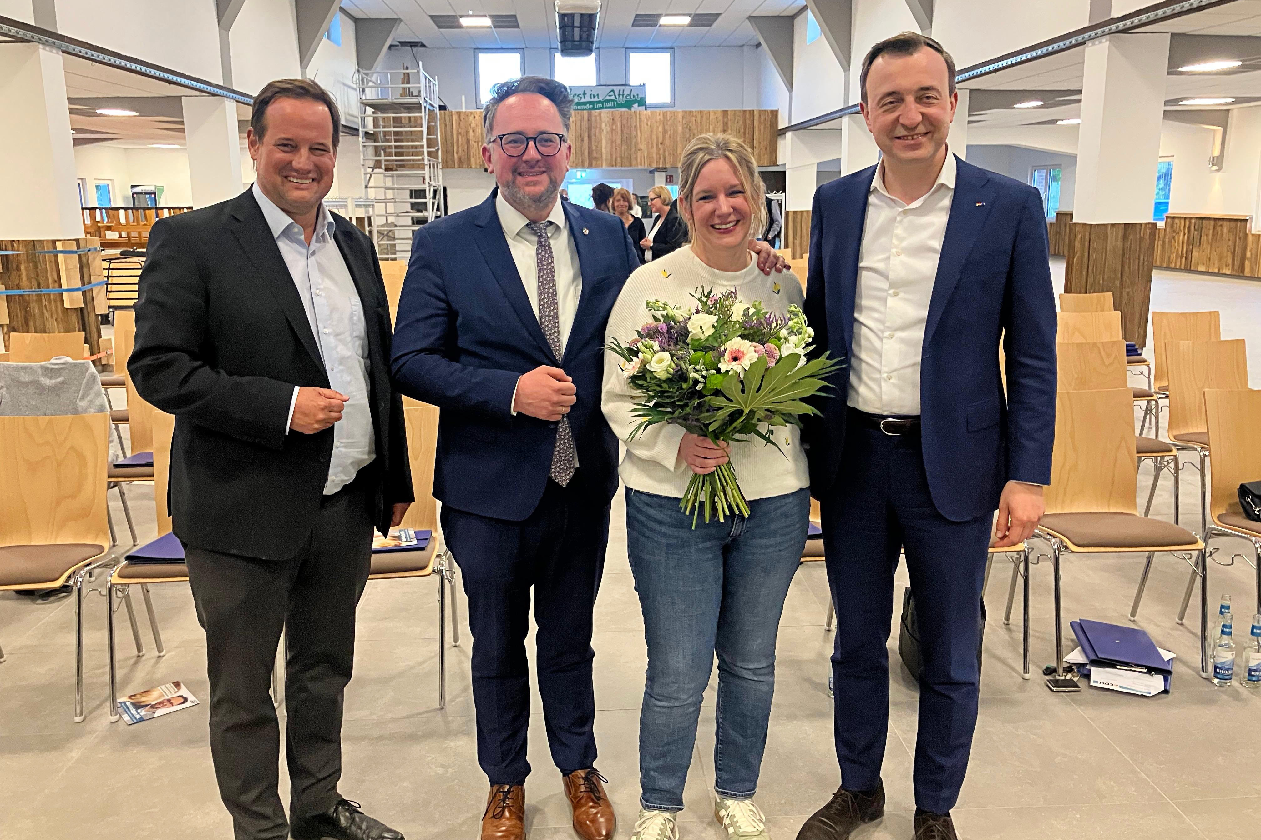 Matthias Eggers, umgeben von Paul Ziemiak, seiner Frau Marjan und Thorsten Schick, hält einen Blumenstrauß in einer Schützenhalle.