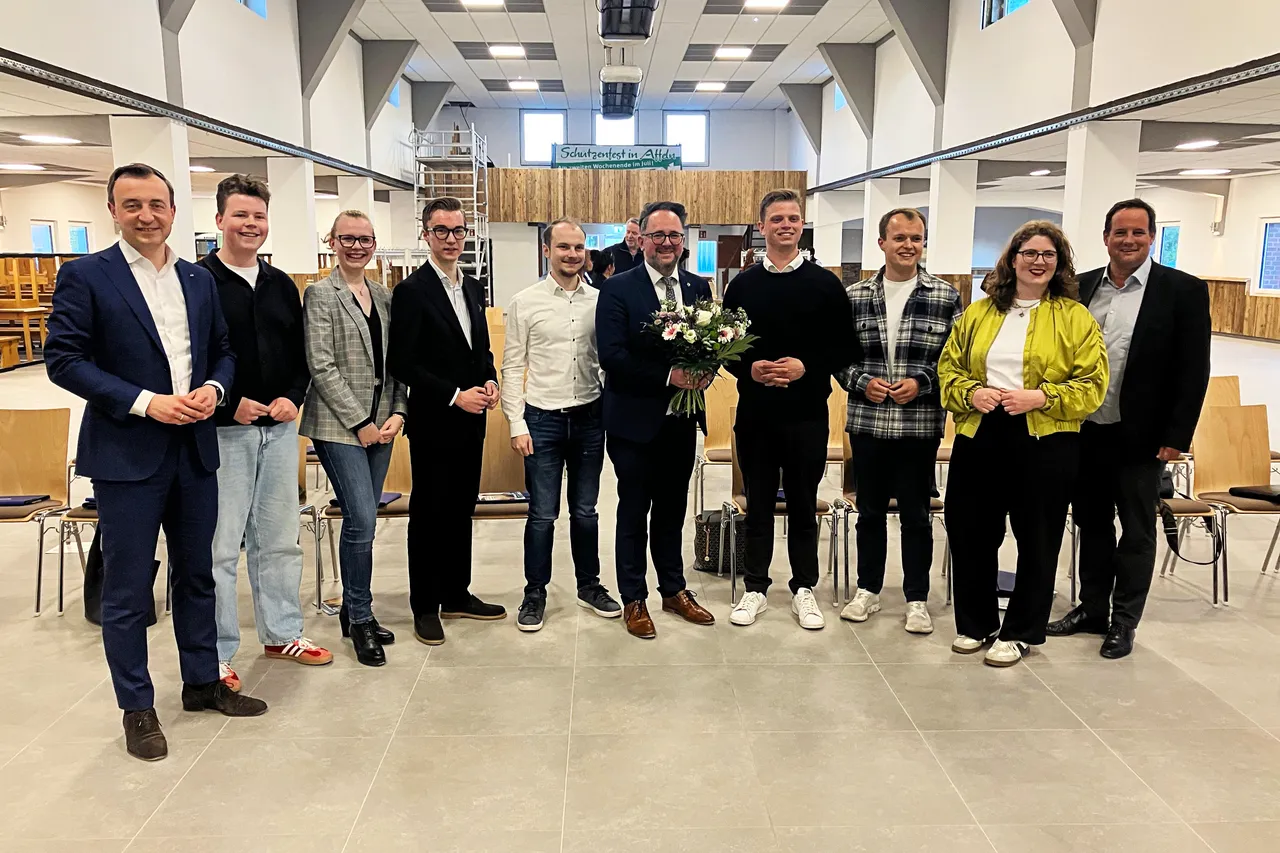 Matthias Eggers, CDU-Kandidat für den Landtagswahlkreis 122, hält in der Schützenhalle Affeln einen Blumenstrauß, umgeben von Parteimitgliedern.