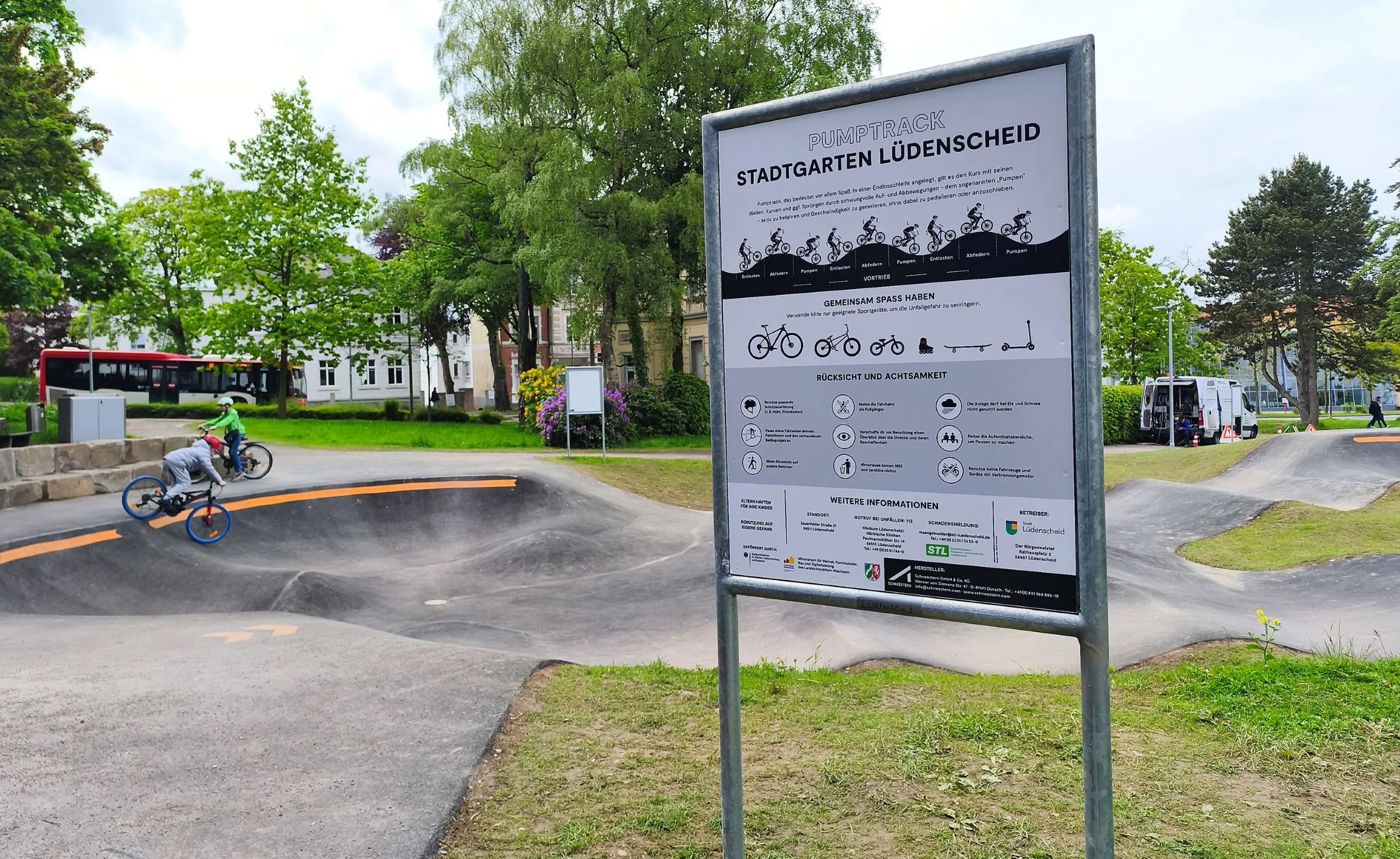 Ein Junge fährt auf einem Pumptrack im Stadtgarten, im Hintergrund ein Informationstafel mit Hinweisen zur Nutzung der Anlage.