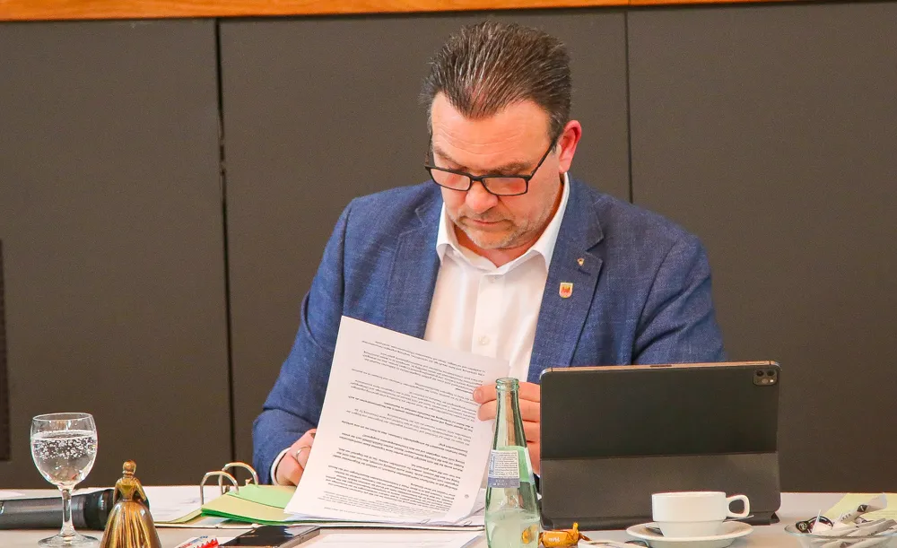 Michael Joithe liest ein Dokument und blickt auf ein Tablet während einer Veranstaltung.