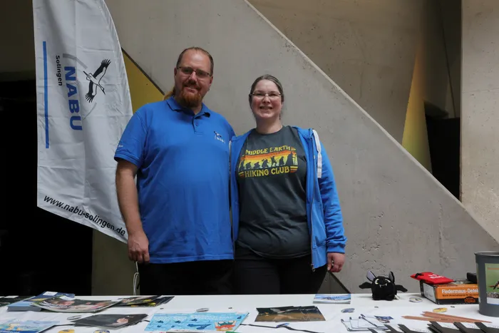 Ein Mann und eine Frau stehen hinter einem NABU-Infostand mit Flyern und Informationsmaterialien bei der Batnight.