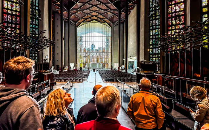 Innenraum der Neuen Kathedrale mit Blick vom Altar auf die leeren Kirchenbänke und ein großes Buntglasfenster.