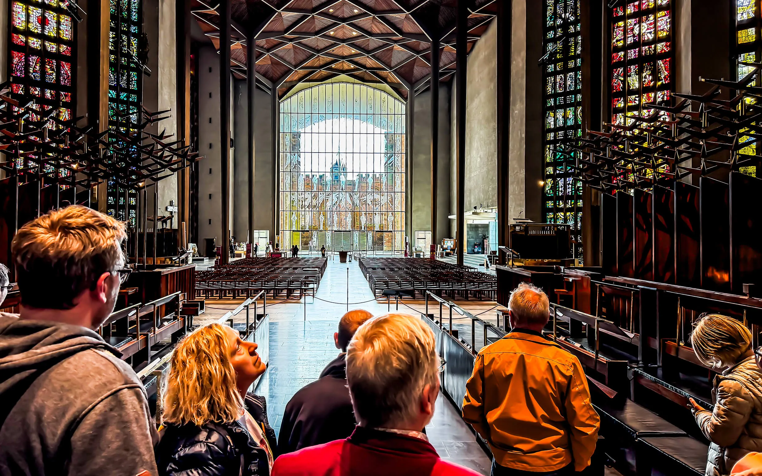 Innenraum der Neuen Kathedrale mit Blick vom Altar auf die leeren Kirchenbänke und ein großes Buntglasfenster.