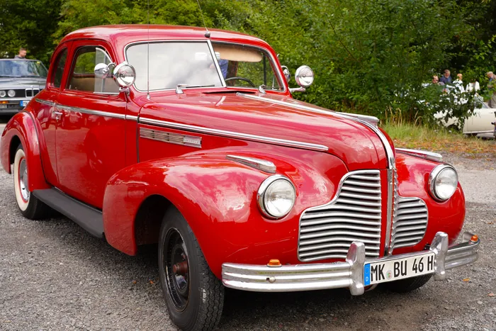 Ein roter Buick aus dem Jahr 1940 mit markantem Chromgrill und Weißwandreifen.