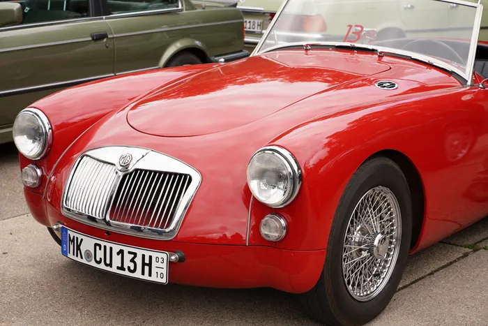 Ein rotes MG-Cabriolet mit Chromgrill und Speichenrädern bei einem Oldtimer-Treffen.
