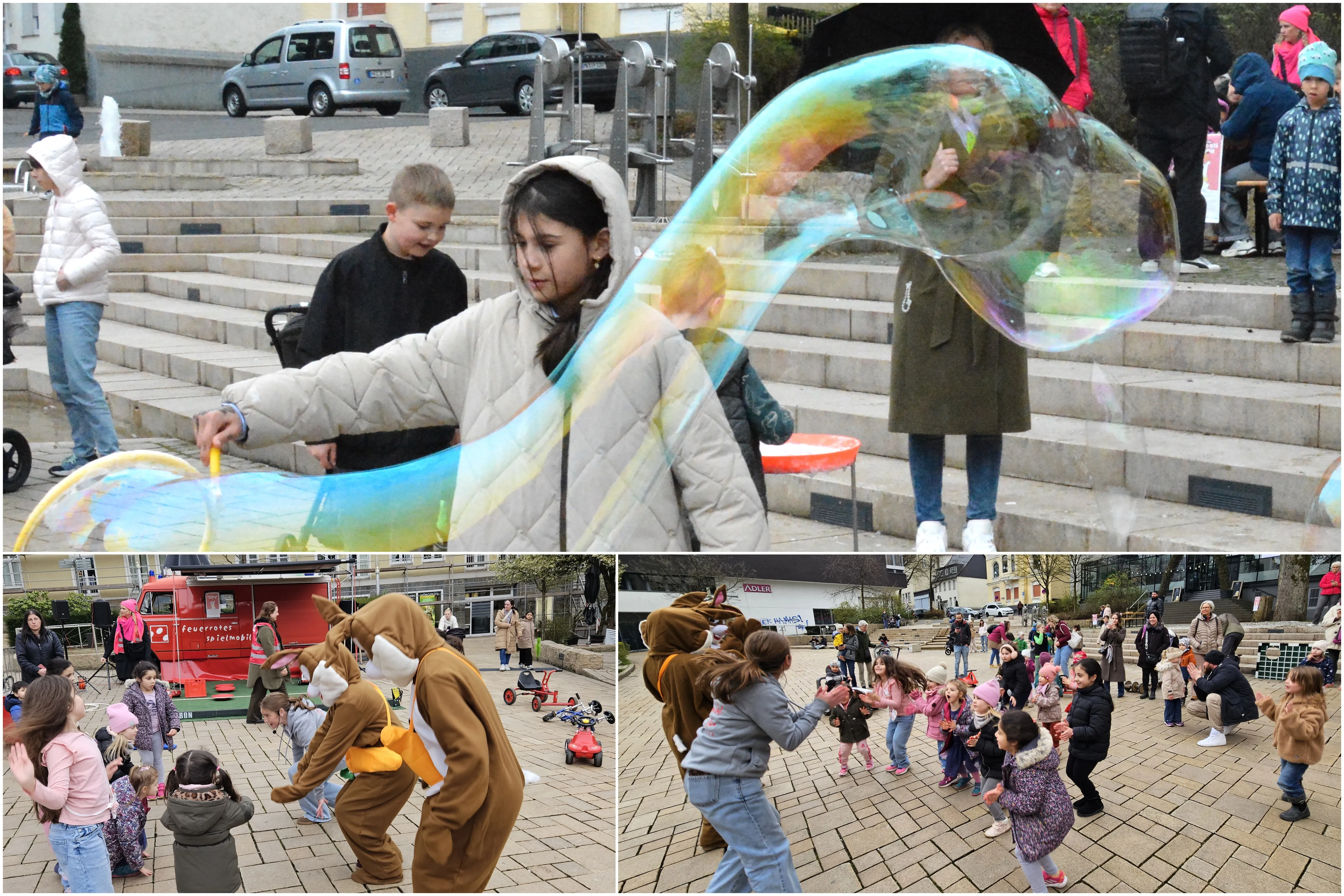Kinder tanzen und spielen im Rosengarten, zwei Personen in Osterhasenkostümen sind dabei. Im Hintergrund steht das Spielmobil und eine Gruppe schaut zu.
