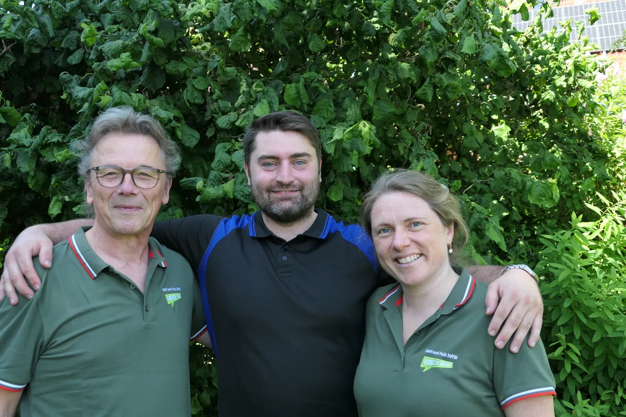 Drei Personen stehen vor einer grünen Hecke. Links Ulrich Ackfeld, in der Mitte Yannick Prümers und rechts Julia Böning, alle mit Poloshirts und lächelnd.