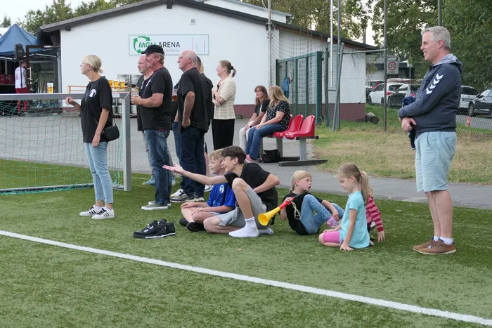 Erwachsene und Kinder versammeln sich auf einem Kunstrasenplatz vor der MCH Arena während eines Fußballturniers.