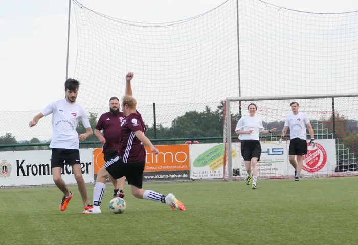 Spieler eines Hobby-Fußballturniers kämpfen auf einem Kunstrasenplatz um den Ball.