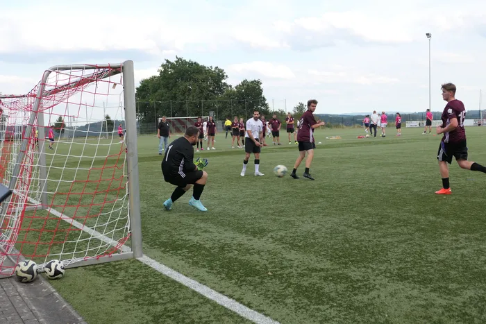 Ein Torwart in schwarzer Kleidung steht vor einem Tor mit rotem Netz auf einem Fußballplatz während eines Turniers.