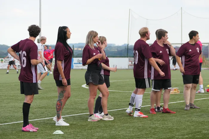 Teilnehmer in weinroten Trikots stehen auf einem Fußballplatz während des TuS Ennepe Hobby-Kicker-Turniers.