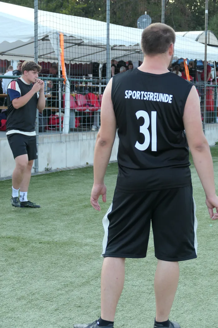 Ein Fußballspieler in einem schwarzen ärmellosen Trikot mit der Aufschrift 'SPORTSFREUNDE 31' steht auf einem Kunstrasenplatz.