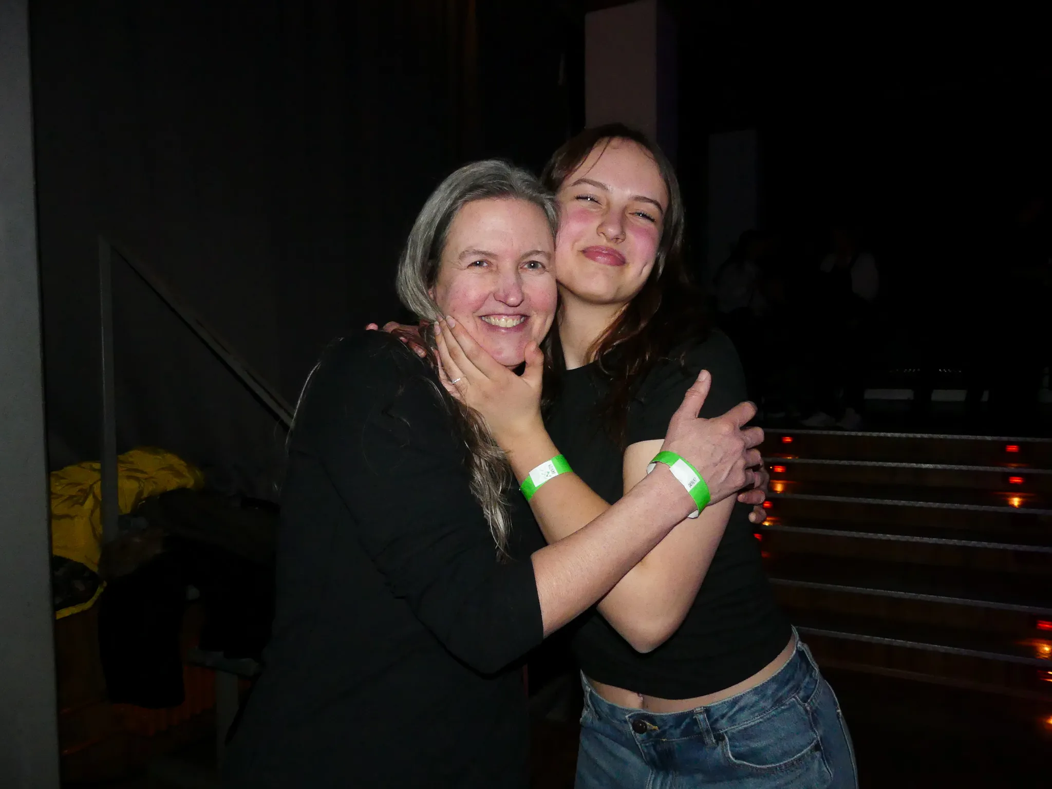 Zwei Frauen umarmen sich lachend auf der Tanzfläche einer 80er-/90er-Party in Kierspe. Die ältere Frau hat graues Haar, die jüngere dunkles Haar und trägt Jeans.