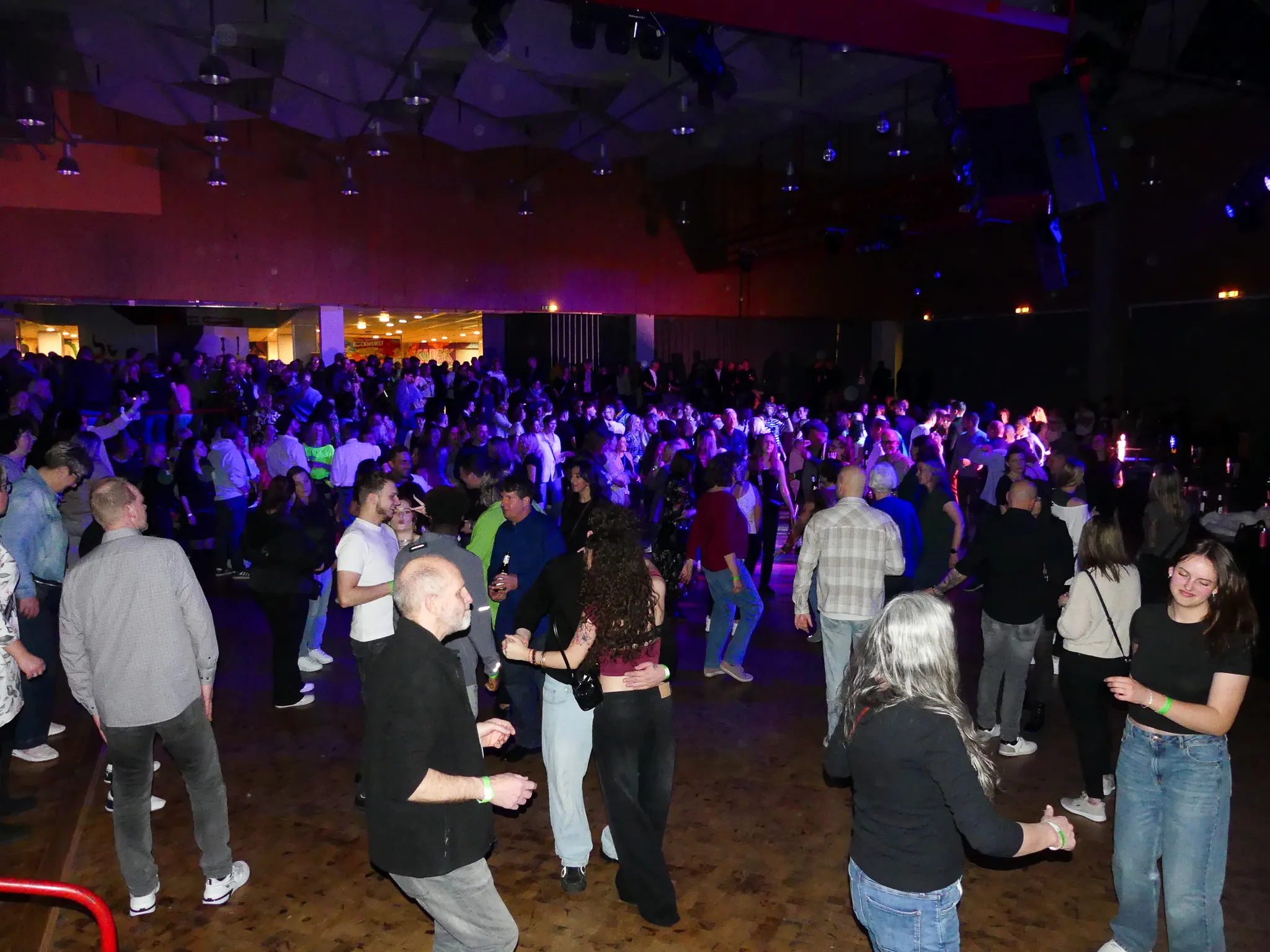 Große Menschenmenge tanzt in einer hell beleuchteten Halle auf einer 80er- und 90er-Jahre-Party in Kierspe.