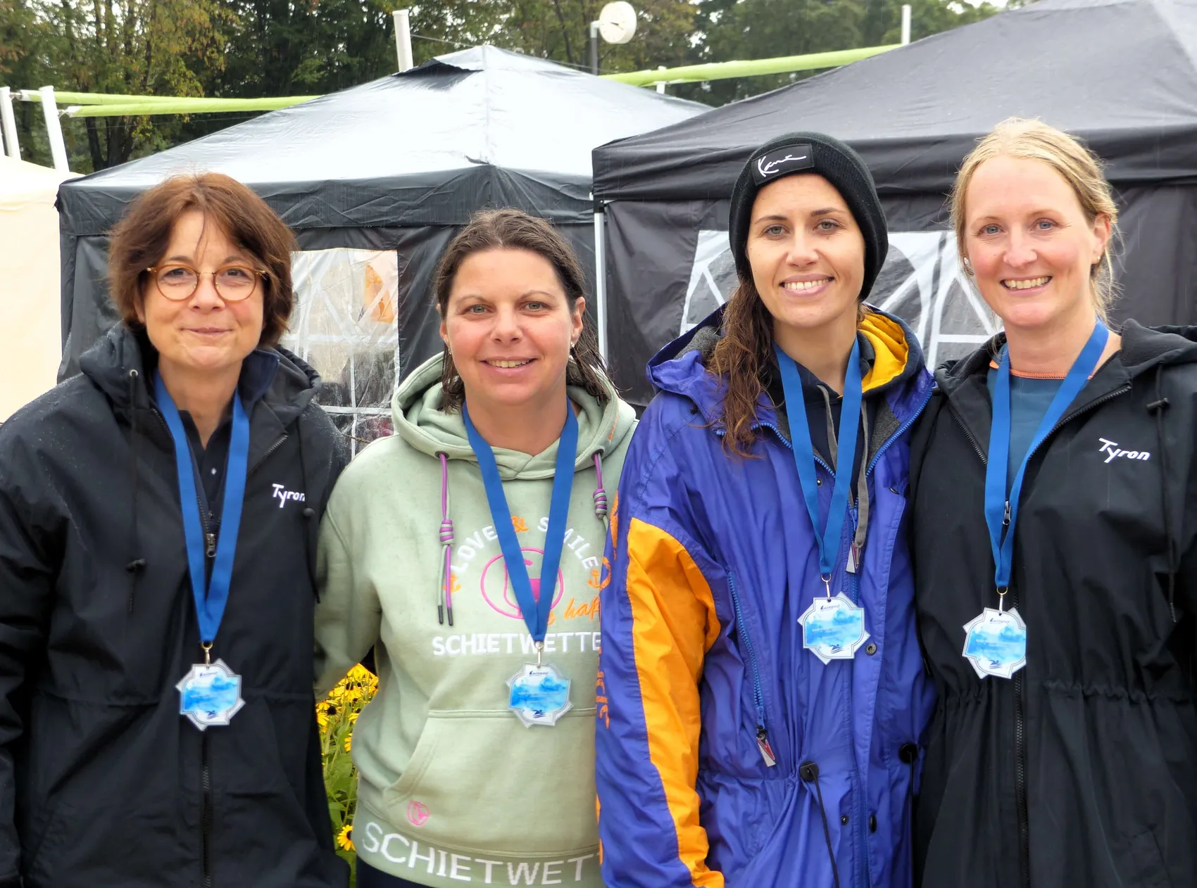 Claudia Zimmermann, Yvonne Grün, Nina Blau und Verena Rohlfs lächeln nebeneinander und tragen Medaillen um den Hals.