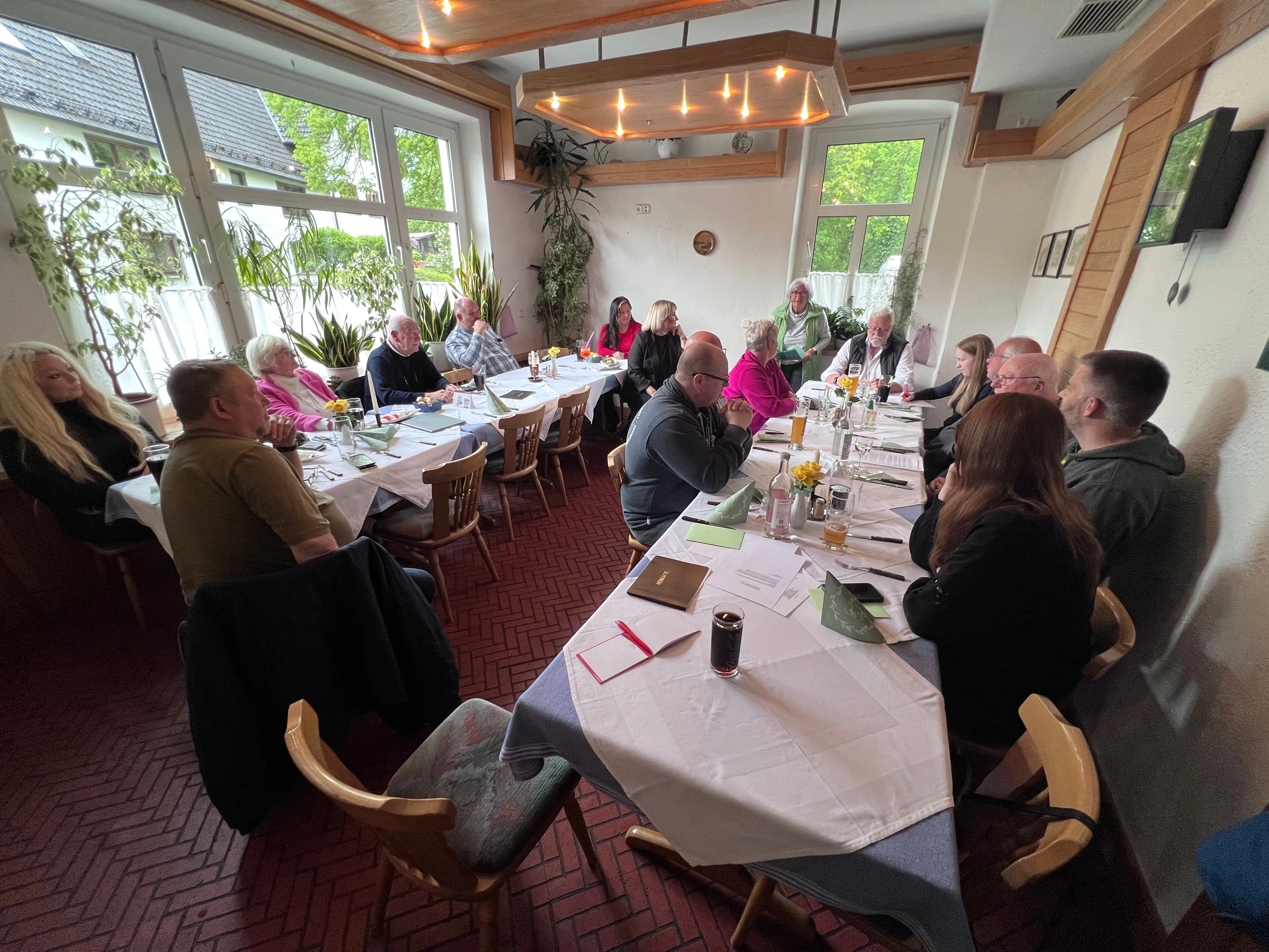 Versammlung der PWG im Haus Wiesenthal mit mehreren Personen an einem langen Tisch, die sich unterhalten und essen.