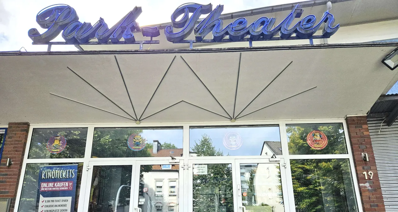 Die Fassade des Park-Theaters mit dem großen blauen Schriftzug über dem Eingang und Plakaten an den Glastüren.