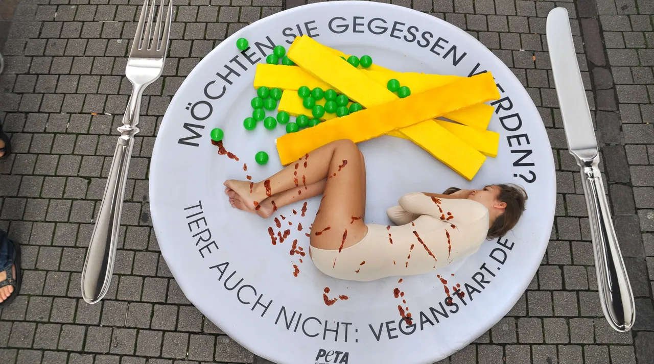 Eine zusammengerollte Person liegt auf einem Teller zwischen gelben Streifen, Erbsen und roten Flecken. Text auf dem Teller: „MÖCHTEN SIE GEGESSEN WERDEN? TIERE AUCH NICHT: VEGANSTART.DE“.