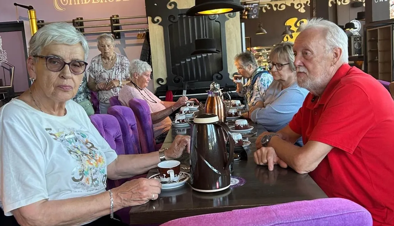 Eine Gruppe älterer Menschen sitzt an einem Tisch in einem Café und unterhält sich bei Kaffee und Kuchen.