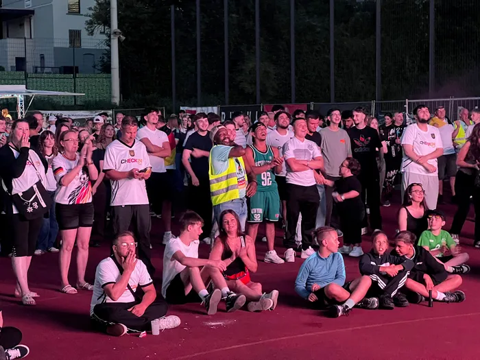 Eine jubelnde Menschenmenge verfolgt ein Spiel bei einer Public-Viewing-Veranstaltung. Viele Fans tragen Trikots der deutschen Nationalmannschaft.
