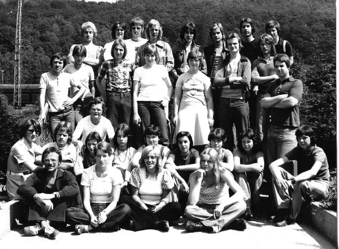Gruppenfoto des Abschlussjahrgangs 1976 der Realschule Plettenberg, bestehend aus etwa 20 jungen Erwachsenen, die vor einem Gebäude posieren.