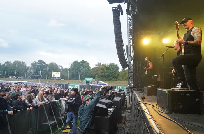 Musiker Rogers spielt Bass auf einer Open-Air-Mainstage vor einer Menschenmenge.