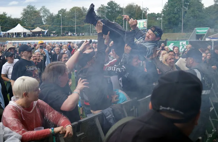 Ein Mann wird von einer Menschenmenge bei einem Open-Air-Festival hochgehalten.