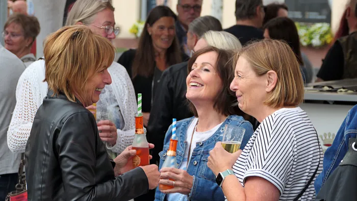 Eine Gruppe lachender Frauen unterhält sich mit Getränken bei der „Roxy Revival Party“.