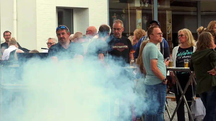 Menschenmenge bei einer Veranstaltung im Freien, teilweise verdeckt durch dichten weißen Rauch im Vordergrund.