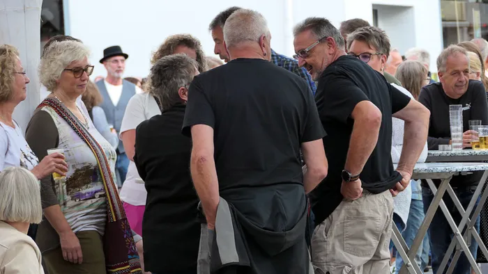 Eine Gruppe von Menschen steht in lockerer Runde zusammen und unterhält sich bei einer Veranstaltung.