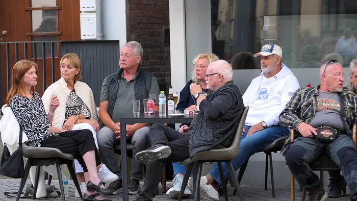 Eine Gruppe von Menschen sitzt an Tischen im Freien bei der „Roxy Revival Party“.