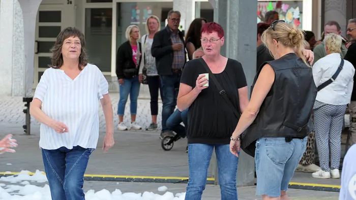 Personen bei der „Roxy Revival Party“, darunter eine Frau in einem weiß gestreiften Oberteil und eine Frau in einem schwarzen T-Shirt mit einem Becher.