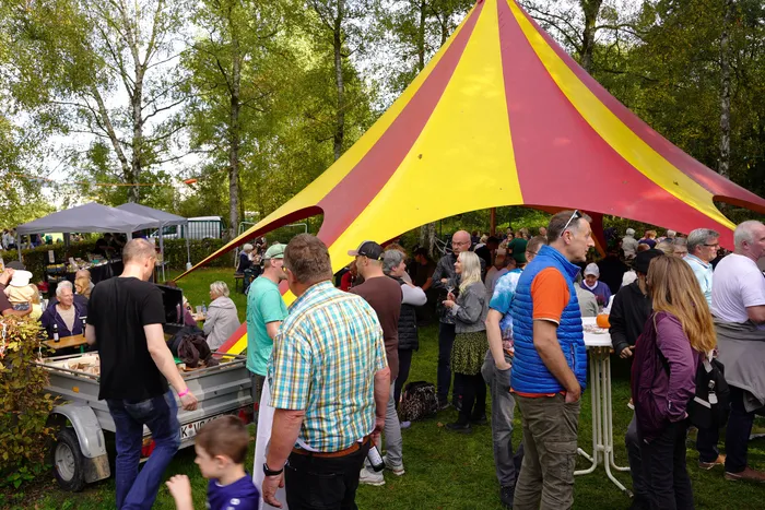 Viele Besucher stehen vor einem großen rot-gelb gestreiften Zelt bei einem Kartoffelfest.
