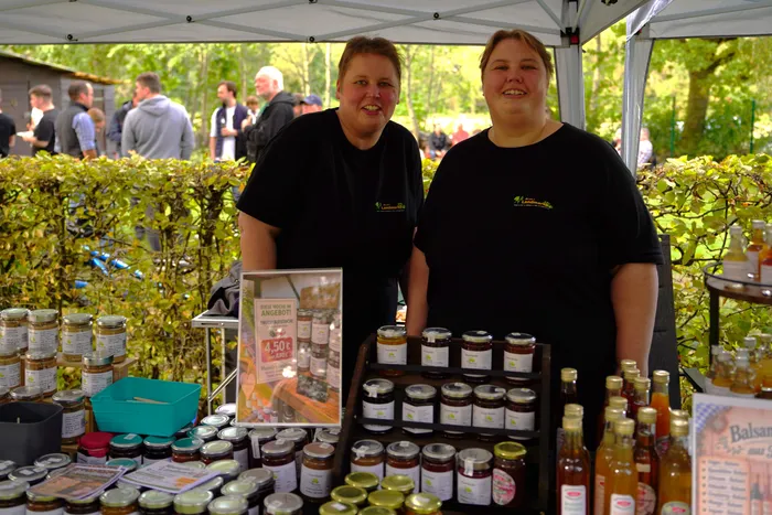 Zwei lächelnde Frauen stehen hinter einem Stand mit Gläsern und Flaschen auf dem Kartoffelfest des SGV Elsetal.