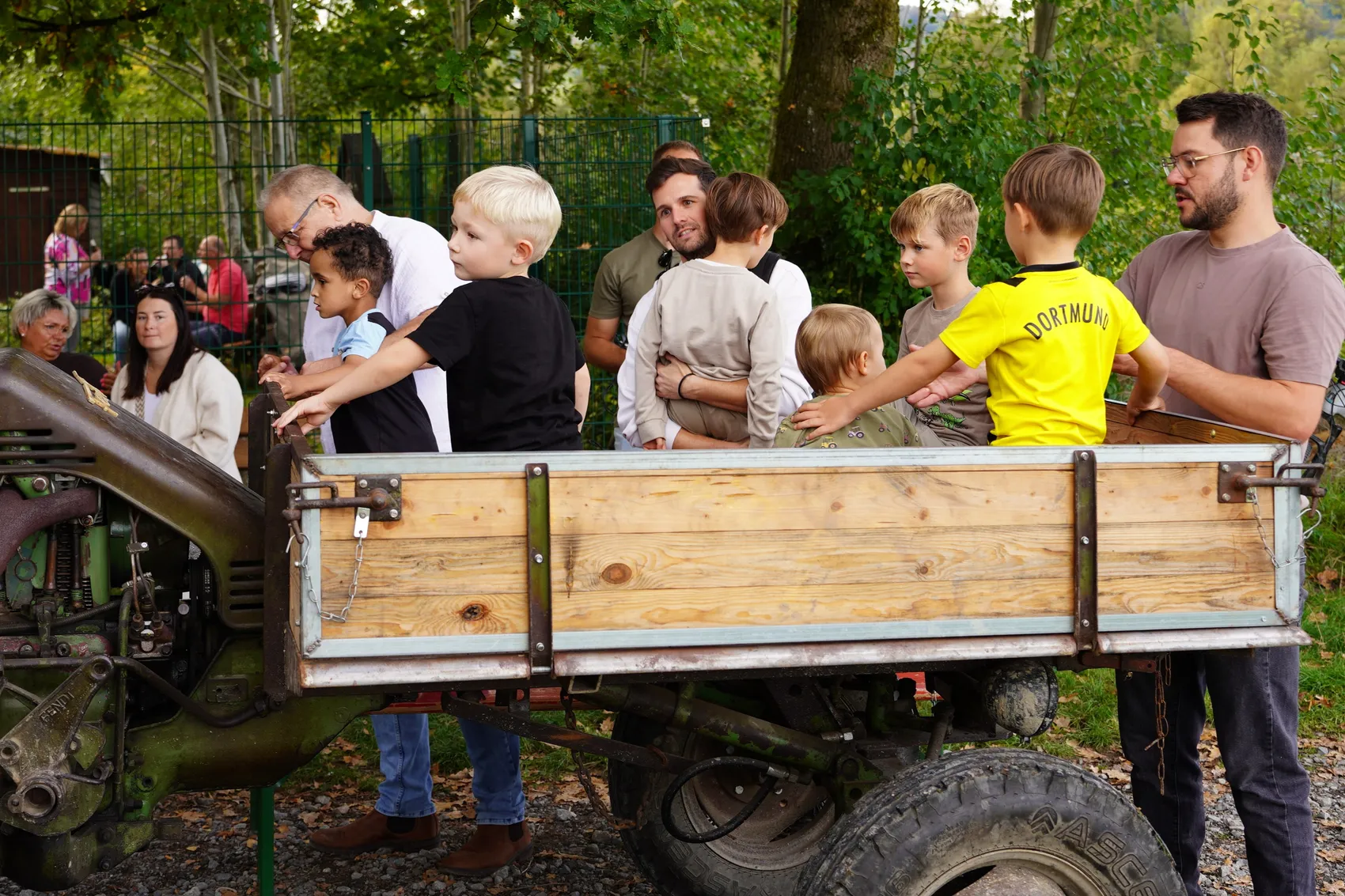 Kinder und Erwachsene stehen um einen hölzernen Anhänger eines Traktors bei einem Kartoffelfest.