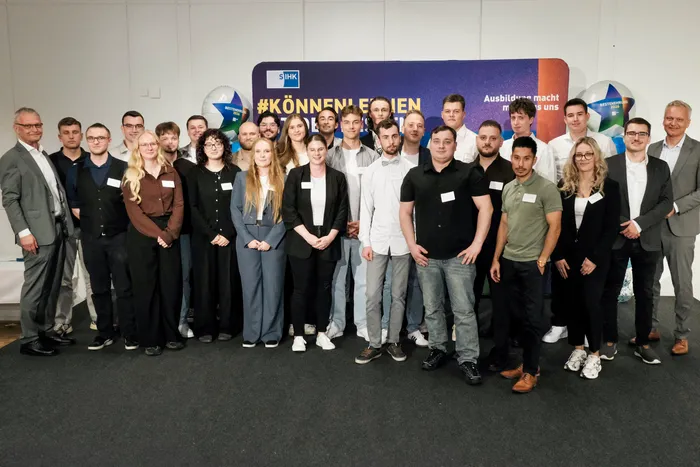 Eine Gruppe von Auszubildenden und Begleitpersonen posiert vor einem blauen Banner mit der Aufschrift „#KÖNNENLERNEN“.