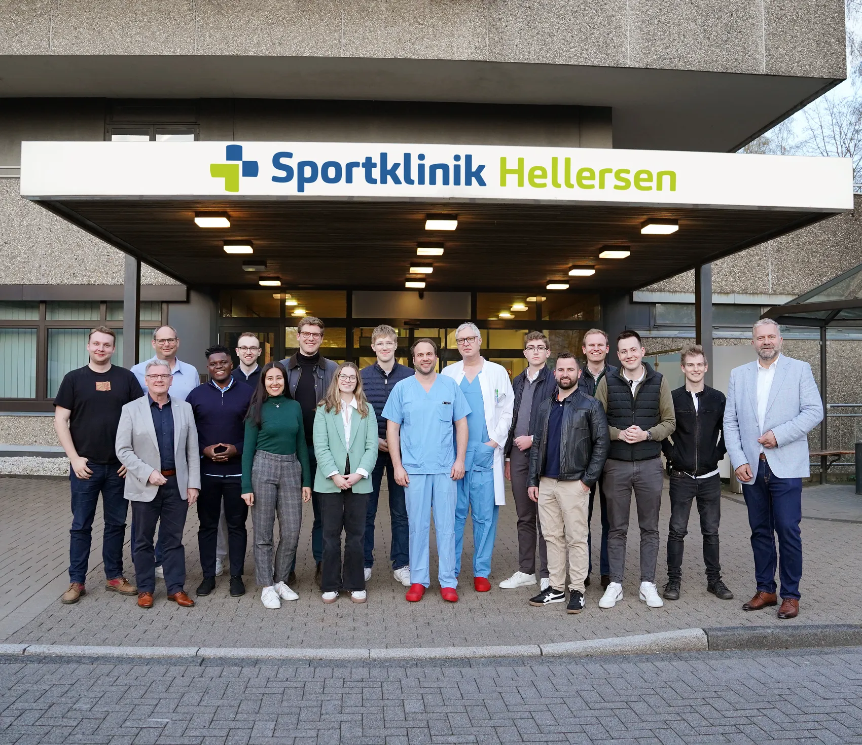 Gruppe von etwa zwanzig Personen vor dem Eingang der Sportklinik Hellersen, darunter ein Mann in OP-Kleidung. Im Hintergrund ein Schild mit dem Kliniknamen.