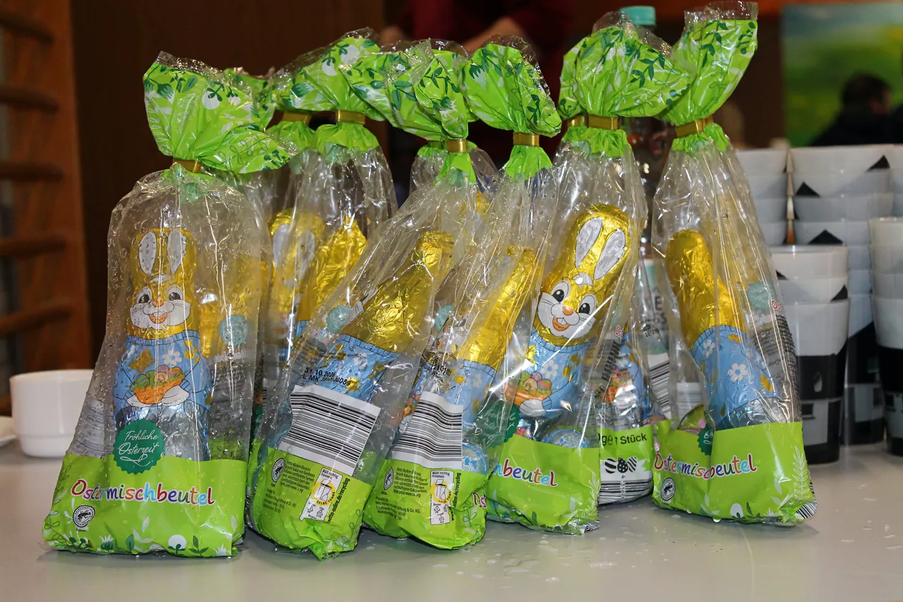 Mehrere grüne Tüten mit Schokoladenostereiern und Hasenmotiven stehen auf einem Tisch, vermutlich als Teil einer Osteraktivität für Kinder und Familien.