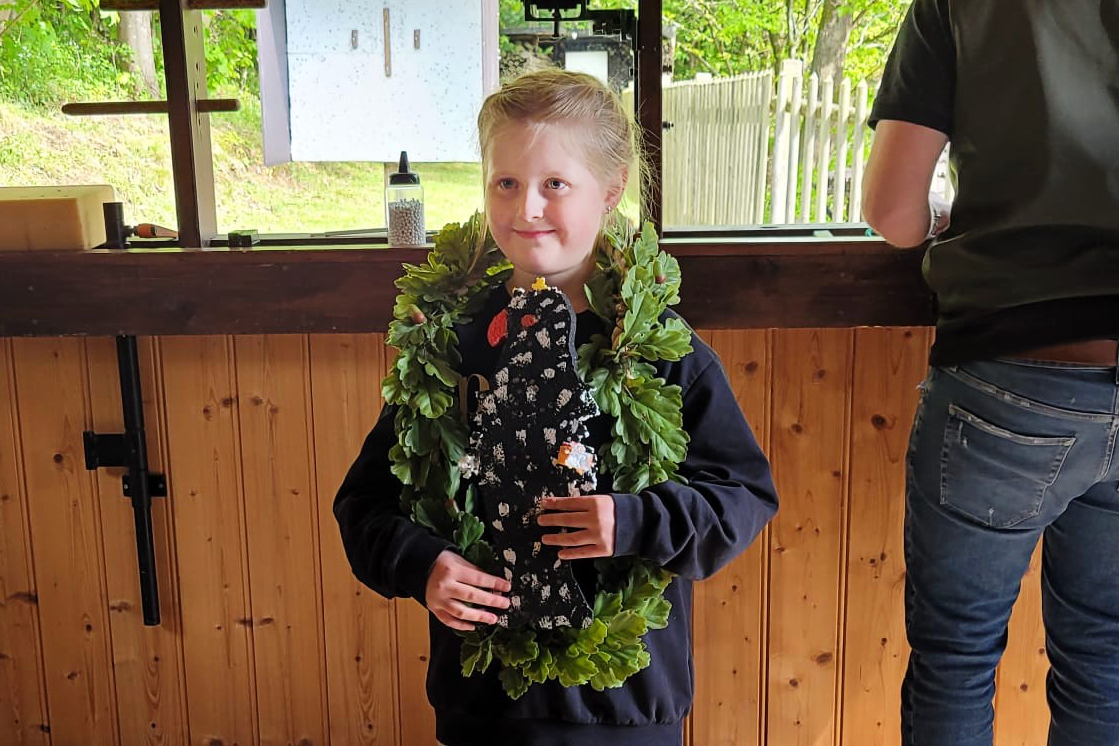 Lina Hagemann, die neue Kinderschützenkönigin, lächelt mit einer Ehrenkette aus Blättern um den Hals.