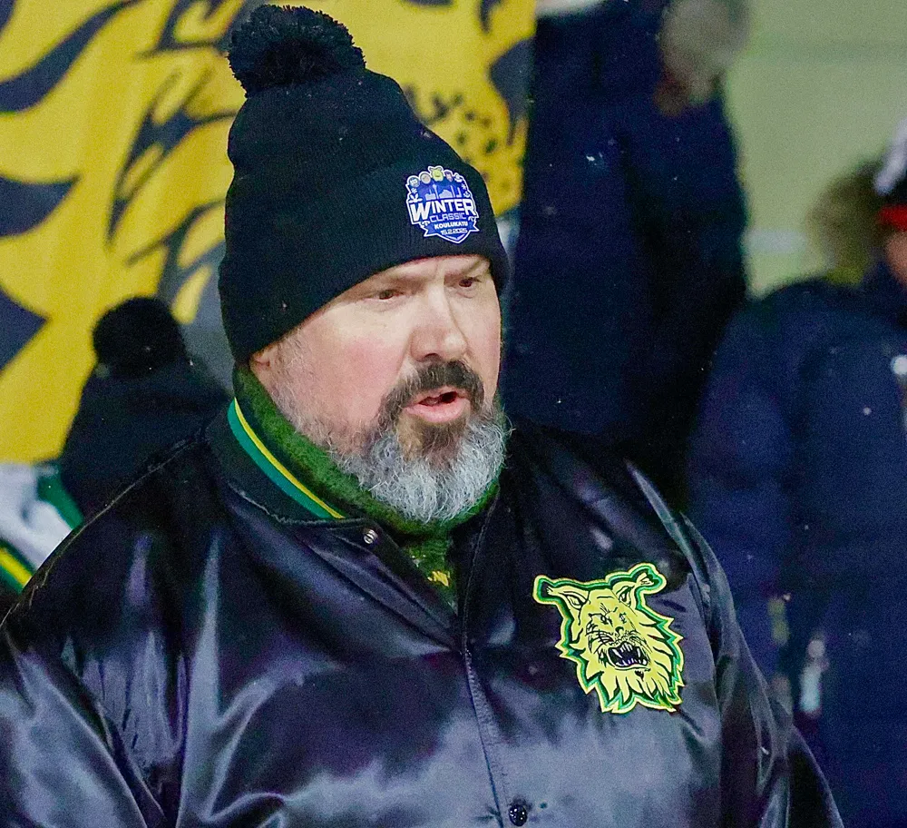Samuli Simula, ein Mann mit grauem Bart und Mütze mit dem Aufdruck „Winter Classic“, blickt zur Seite. Er trägt eine Jacke mit einem Wappen.