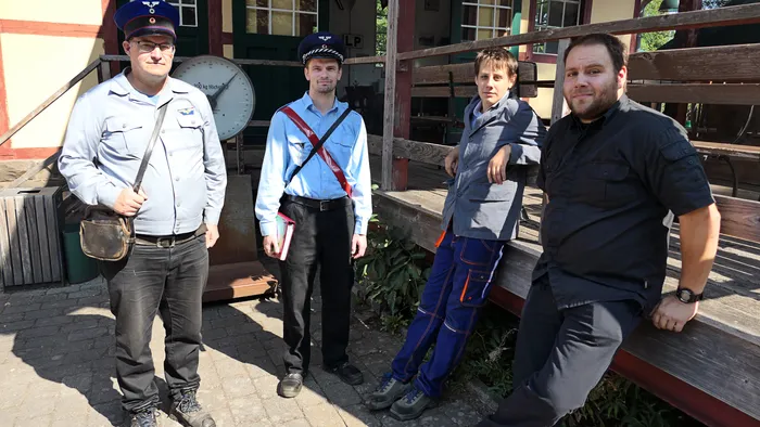 Vier Männer, zwei davon in Uniformen, stehen vor einem Gebäude beim Blaulichttag in Hüinghausen.