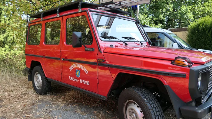 Ein rotes historisches Feuerwehrfahrzeug der Freiwilligen Feuerwehr S. Michele - Appiano.