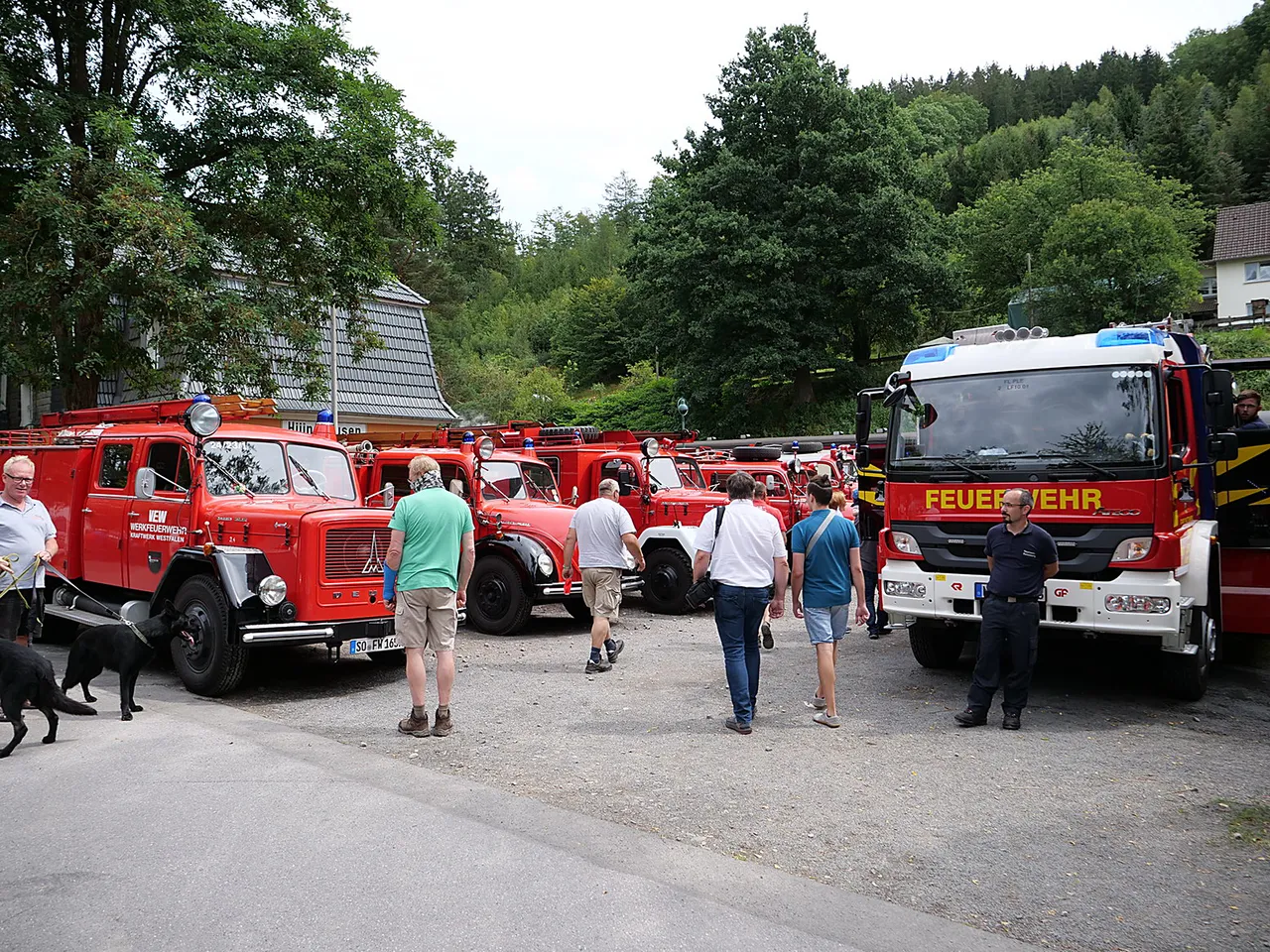 Eine Reihe roter Feuerwehrfahrzeuge, von historischen Modellen bis zu moderner Technik, steht auf einem Platz.